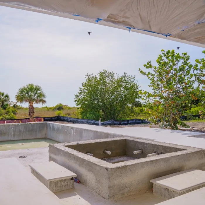 A modern concrete hot tub located on a spacious concrete patio. Elements Oasis design