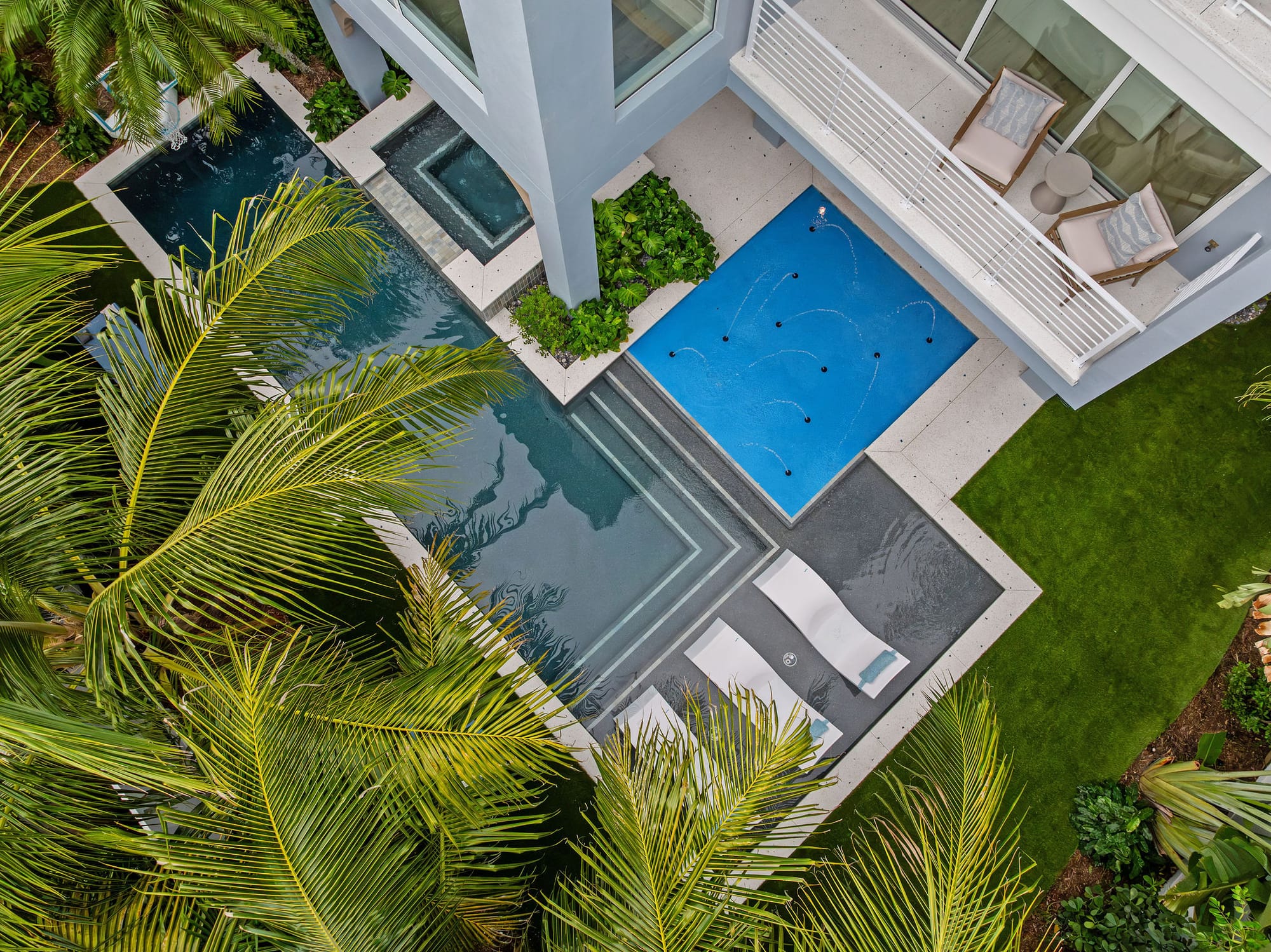 An aerial view of a custom pool, raised spa, and deck-jet splash pool surrounded by tropical landscaping.