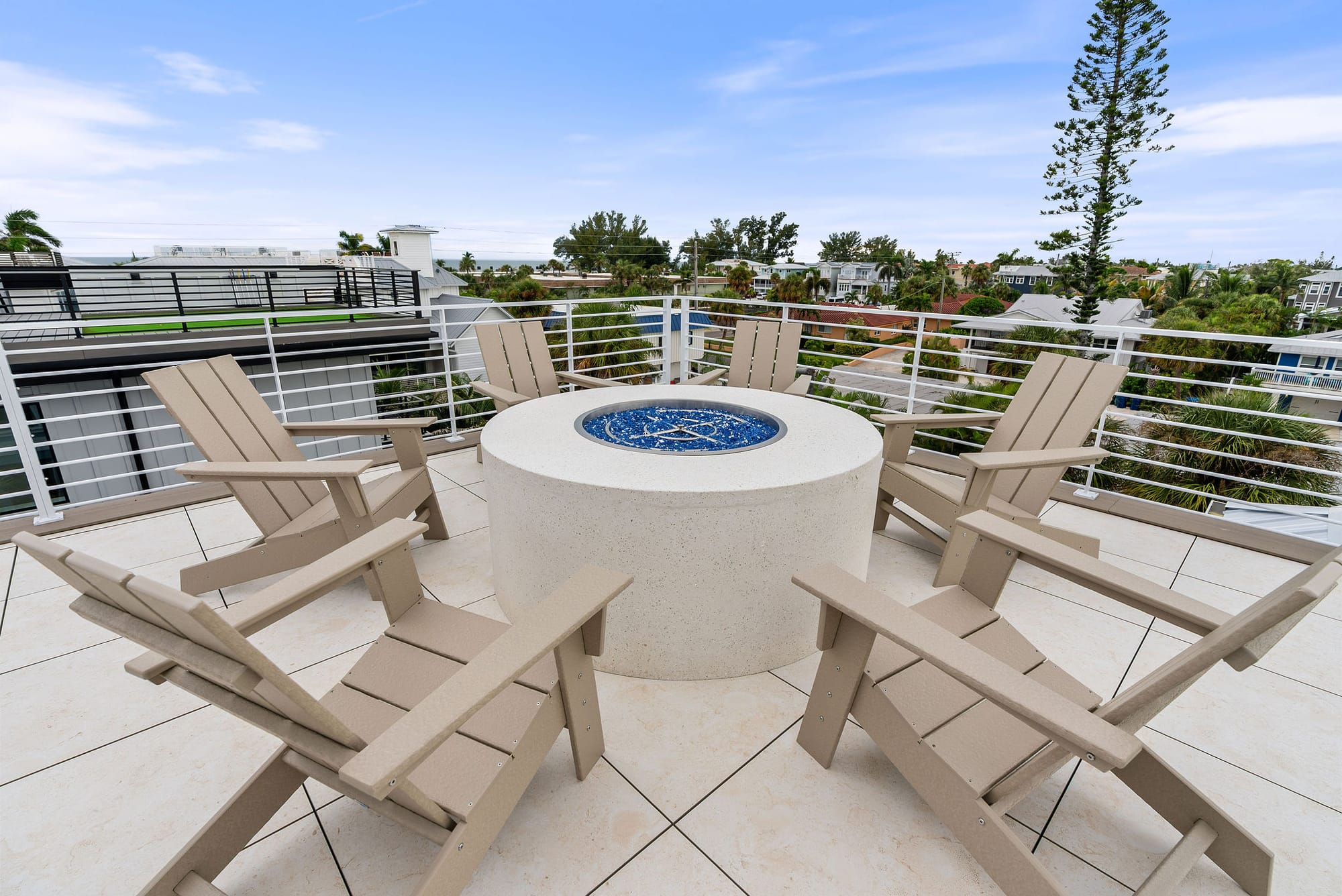 A rooftop fire pit surrounded by Adirondack chairs with views across Anna Maria Island.